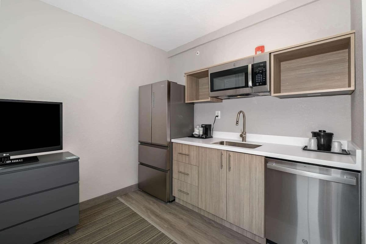 A compact kitchen with a microwave, refrigerator, sink, and dishwasher.