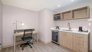 Una cocina compacta equipada con microondas, lavamanos y cafetera.