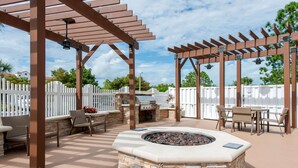 An outdoor patio with a stone fire pit, seating, and a grill area. - Country Inn & Suites by Radisson, Port Canaveral, FL (Cape Canaveral)
