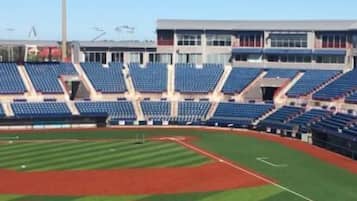 A baseball stadium with multiple tiers of seating, a central field, and a modern building structure in the background.