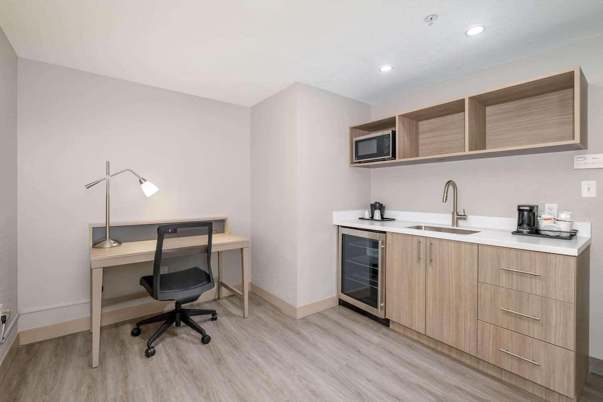 A compact kitchenette with a microwave, sink, and cabinets.