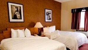 A hotel room with two beds, a nightstand, a lamp, and two framed pictures on the wall. - Sky City Casino Hotel (San Fidel)