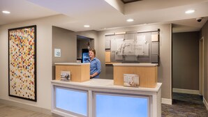 A hotel reception desk with a digital display, a check-in/out sign, and a Holiday Inn Express sign. - Holiday Inn Express Warrenton by IHG (Warrenton)