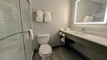Un baño moderno con cabina de ducha de vidrio, inodoro y tocador con espejo.