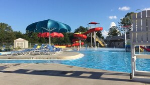 Une piscine avec des toboggans, des parasols et des chaises longues.