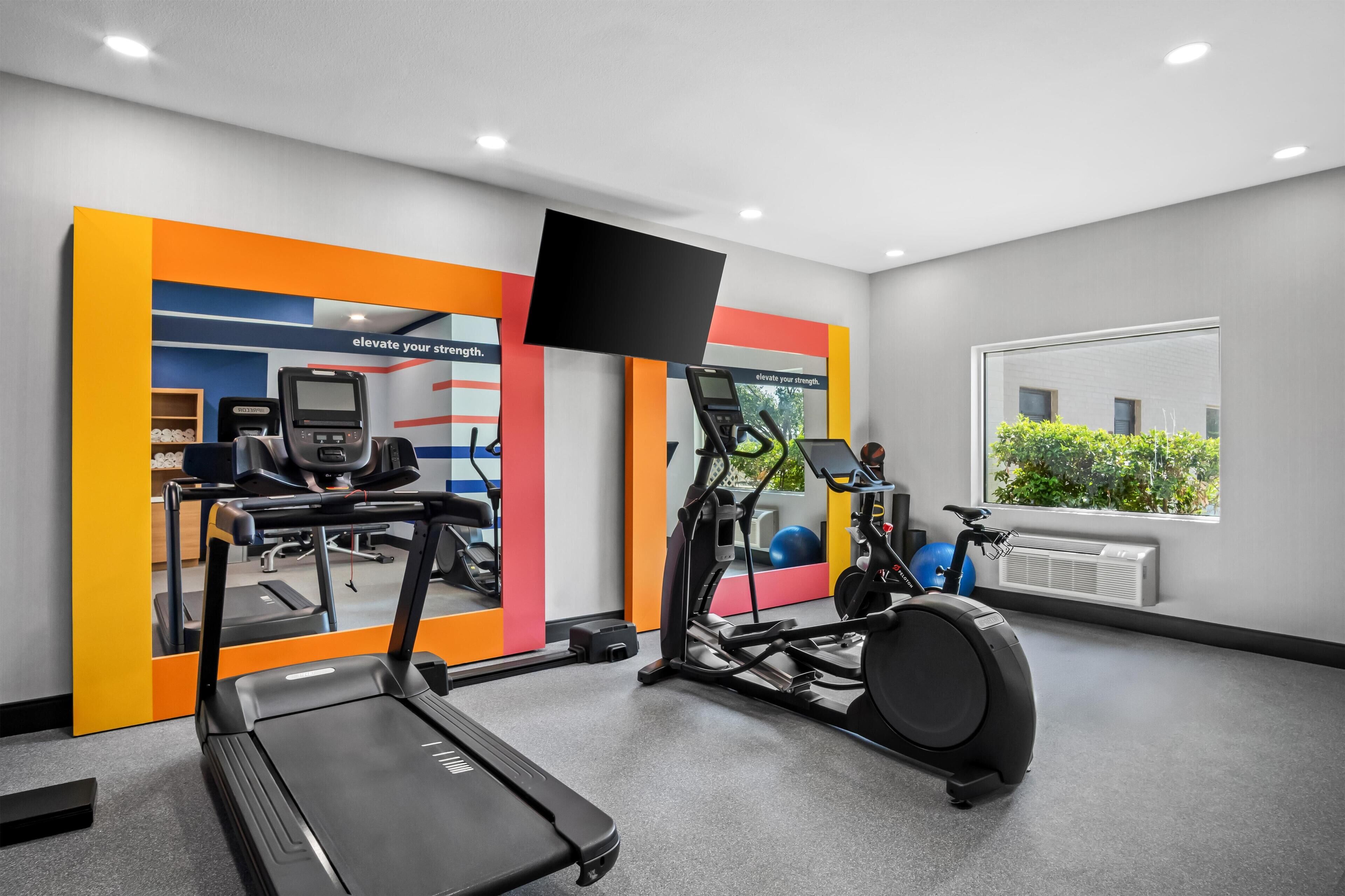 A modern gym with treadmills, an elliptical, and exercise balls.