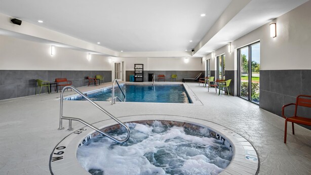 A modern indoor swimming pool with a hot tub, clear glass doors, and bright lighting. - Hampton Inn & Suites Waxahachie (Waxahachie)