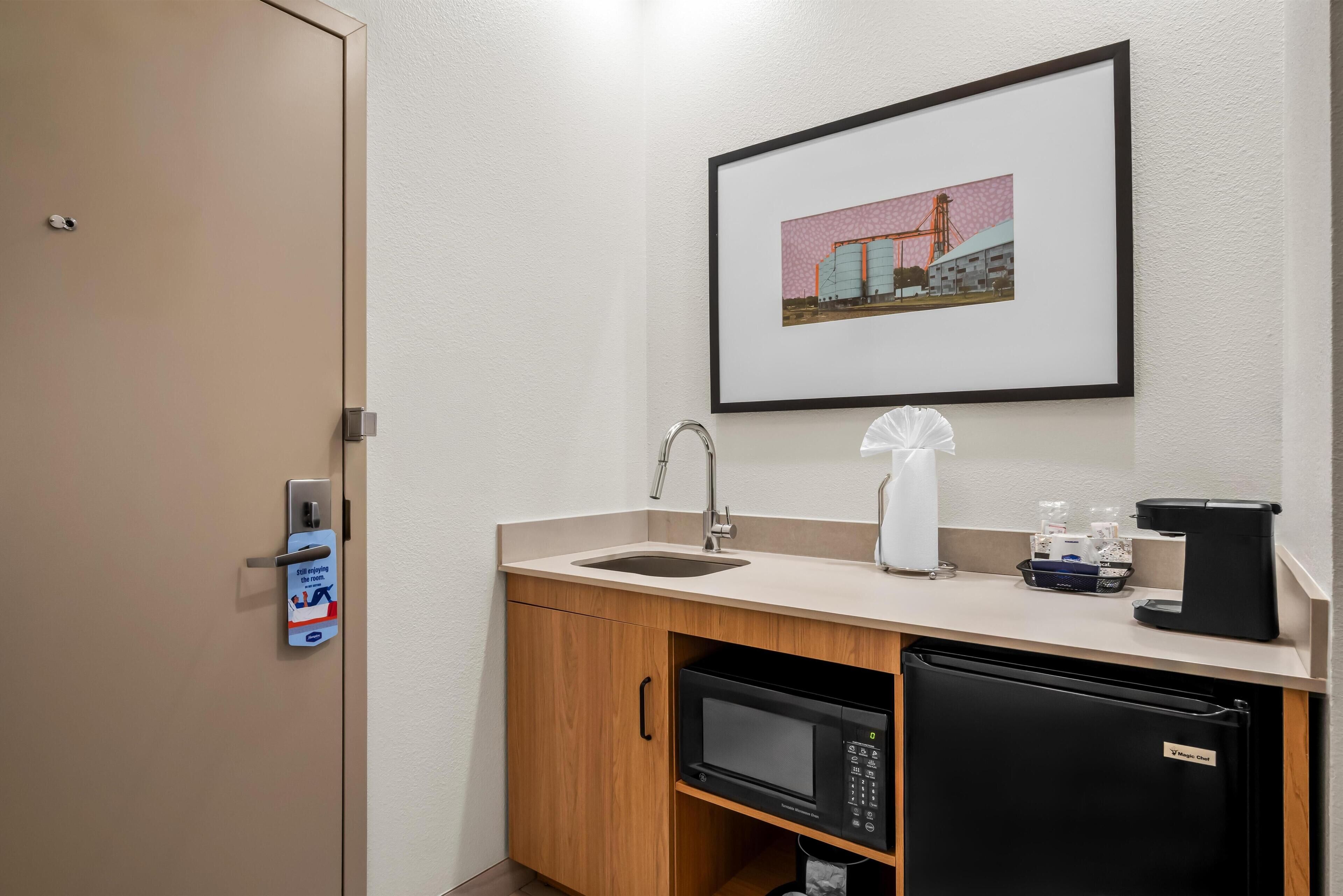 A compact kitchenette with a sink, a microwave, a coffee maker, and a small refrigerator.