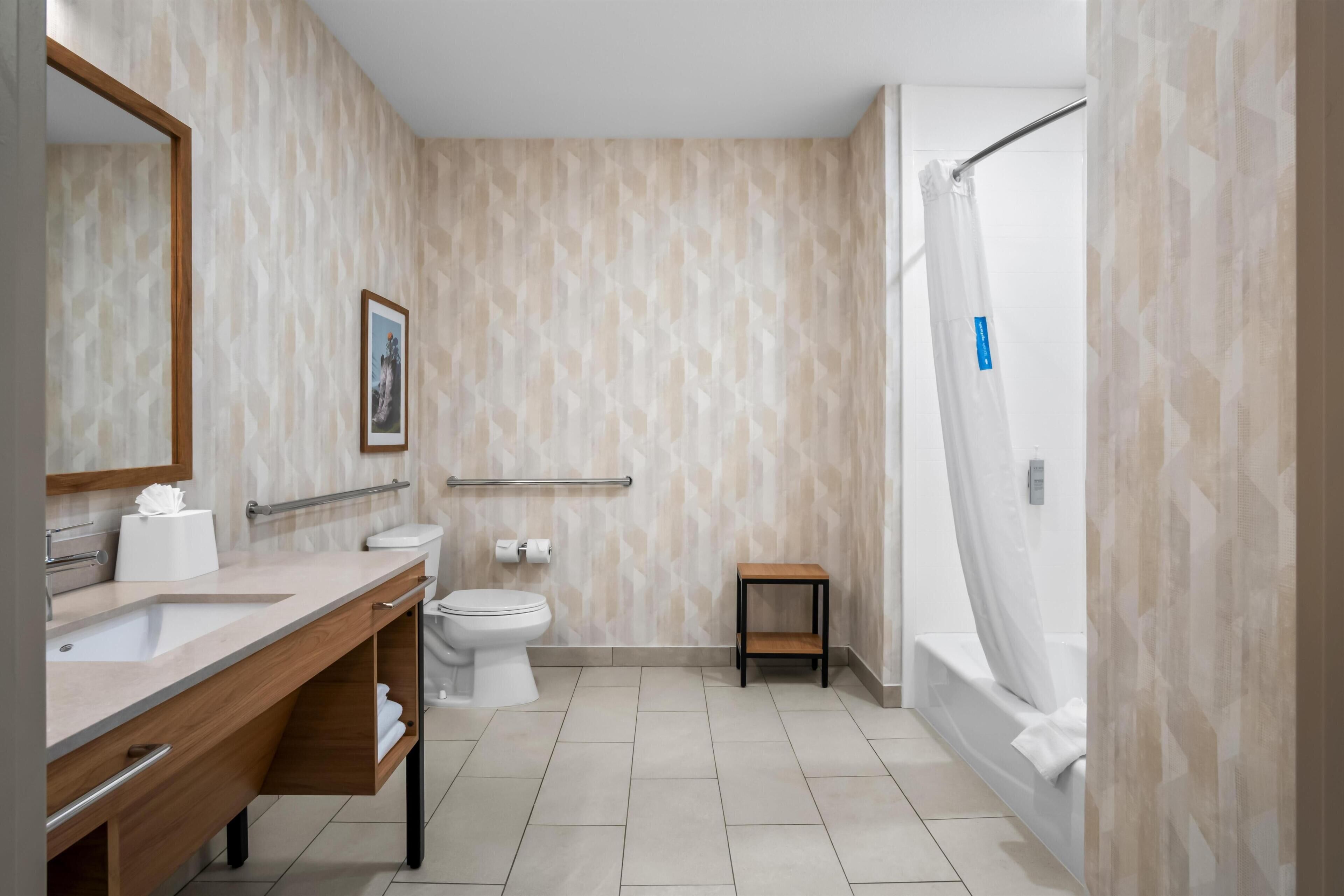 A modern bathroom with a wooden vanity, a toilet, a small wooden stool, and a shower with a curtain.