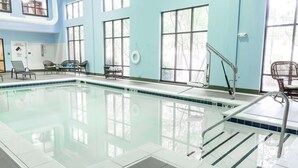 A swimming pool with clear water, surrounded by lounge chairs and a safety railing.