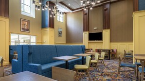 A restaurant with a blue booth seating area, wooden tables, and chairs. - Hampton Inn & Suites Williamsburg Historic District (Williamsburg)