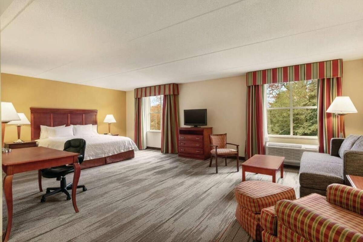Een hotelkamer met een bed, bureau, stoel, televisie en bank.