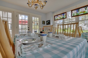 A dining area with a checkered tablecloth, a chandelier, and a view of the outdoors through large windows.