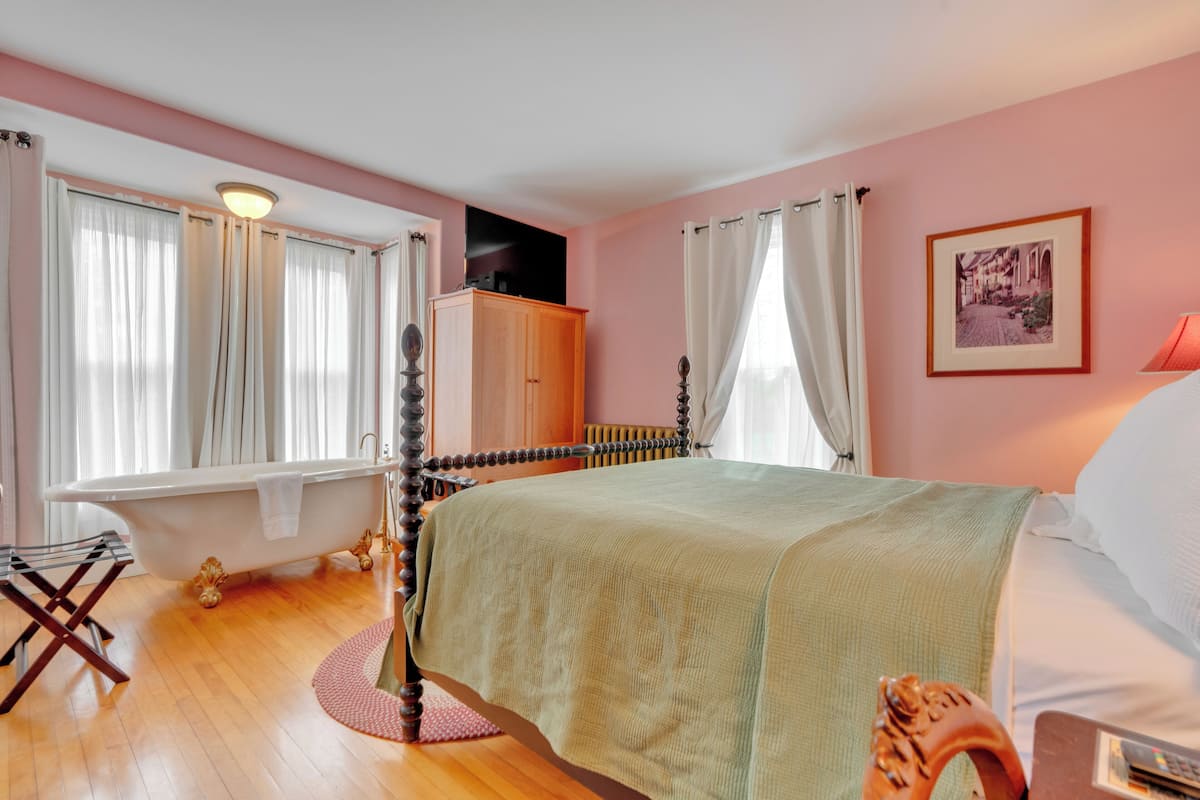 A bedroom with a bed, a wooden wardrobe, a radiator, and a window with curtains.