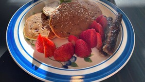 A plate with pancakes, strawberries, and sausages.