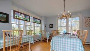 A dining area with checkered tablecloths, wooden chairs, and stained glass windows.