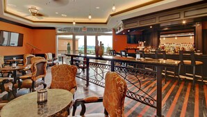 A bar area with a long counter, multiple seating options, and a view of the outdoors.
