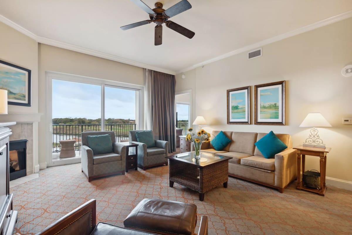 A spacious living room with a fireplace, two sofas, a coffee table, and a ceiling fan.