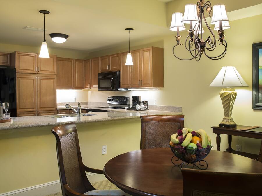 A kitchen with wooden cabinets, a microwave, and a dining area with a table and chairs.
