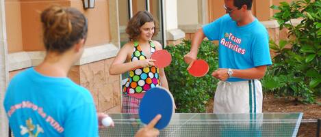 Un groupe de personnes jouant au ping-pong à l’extérieur.