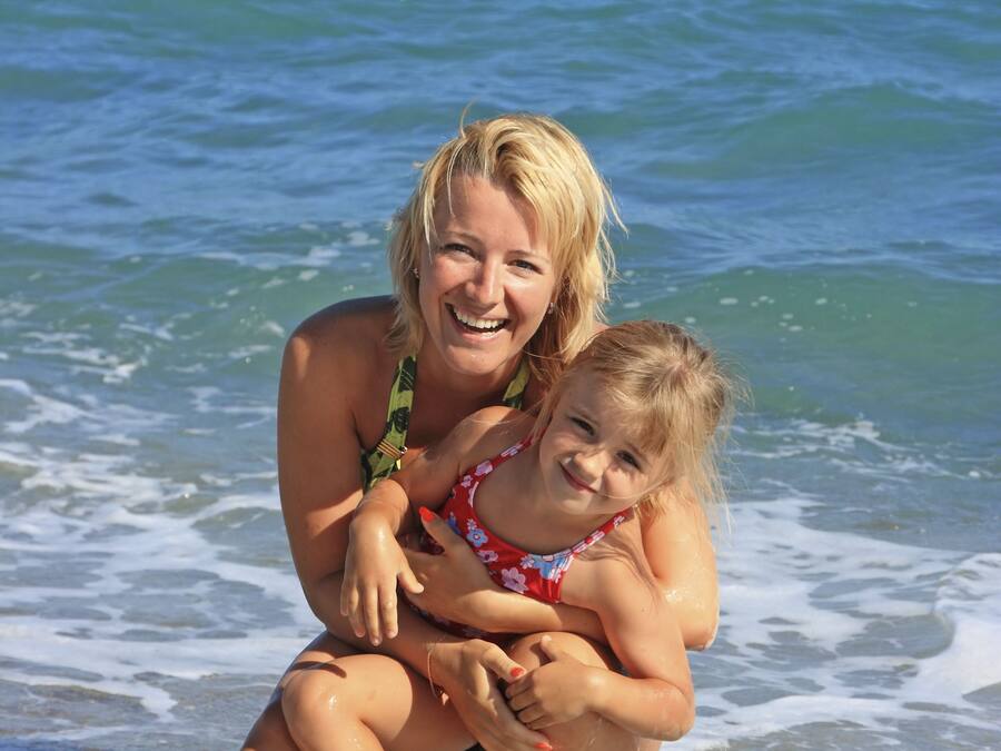 A woman and a child in the water at a beach.