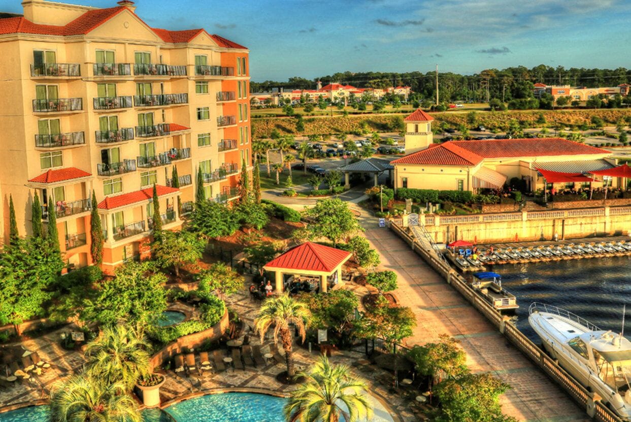 A hotel with multiple balconies, a swimming pool, and a dock with boats.