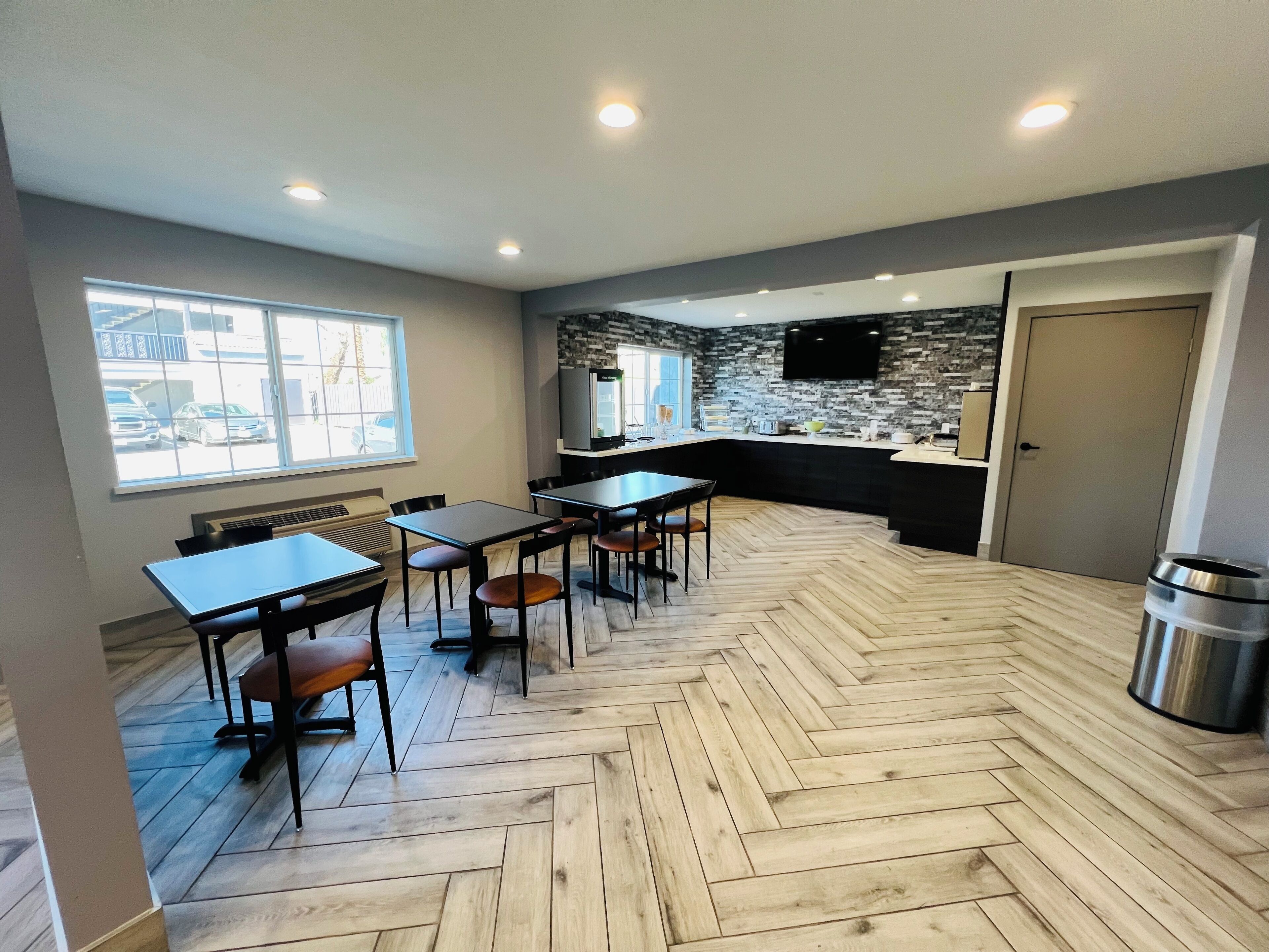 A modern kitchen with a herringbone floor pattern, a built-in island, and a flat-screen TV mounted on the wall.