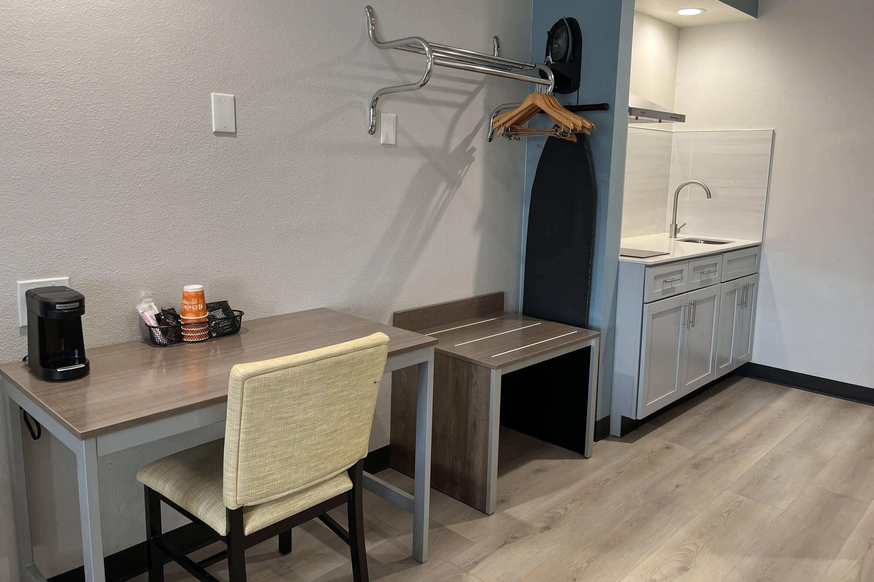 A compact kitchenette with a sink, a coffee maker, and a chair.