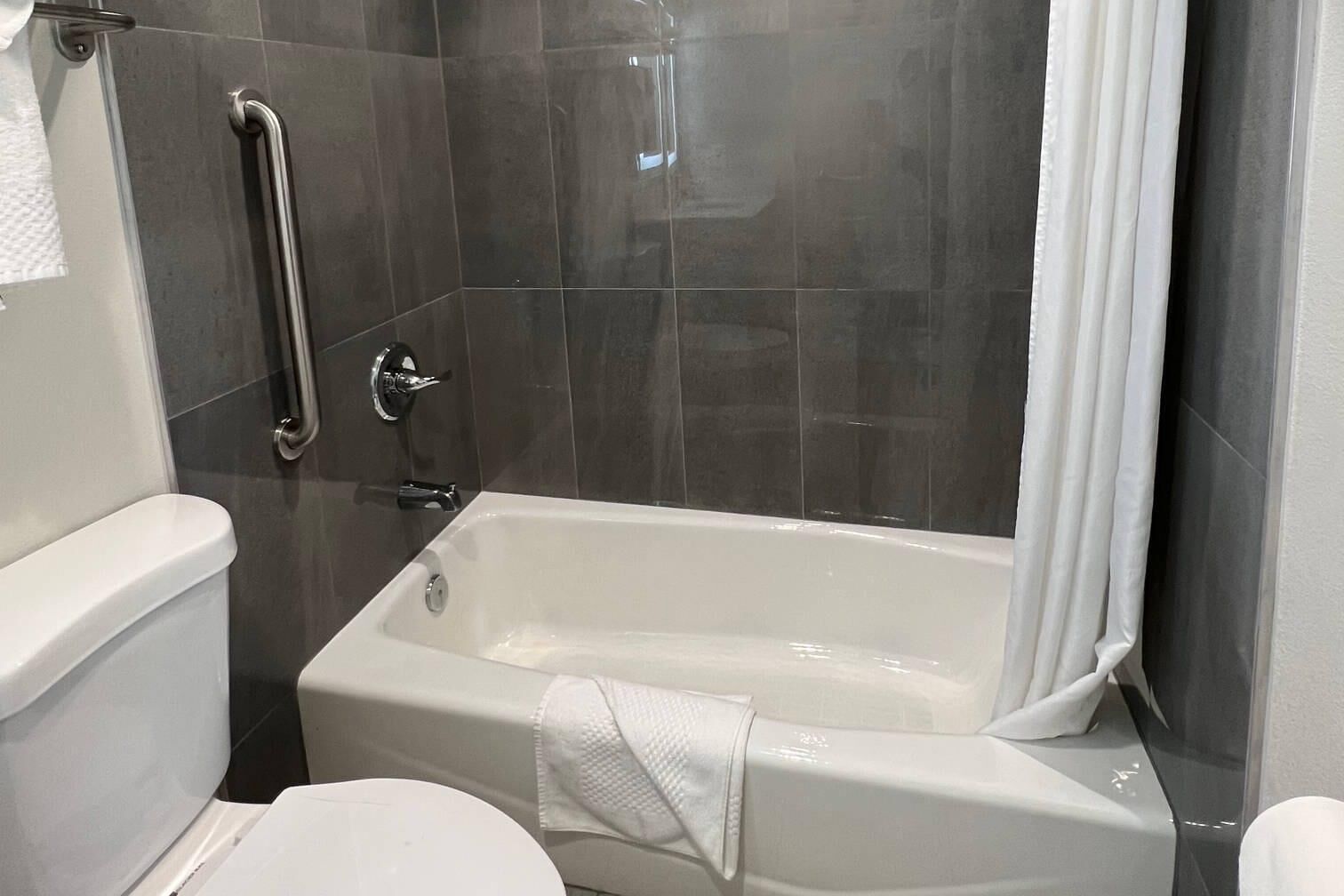A bathroom with a bathtub, a toilet, and a shower area.