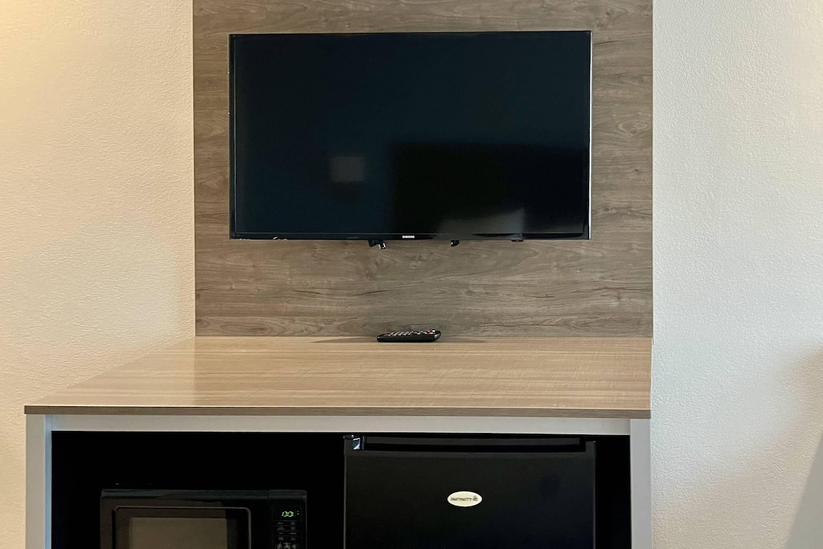 A flat-screen TV mounted on a wooden wall above a microwave.