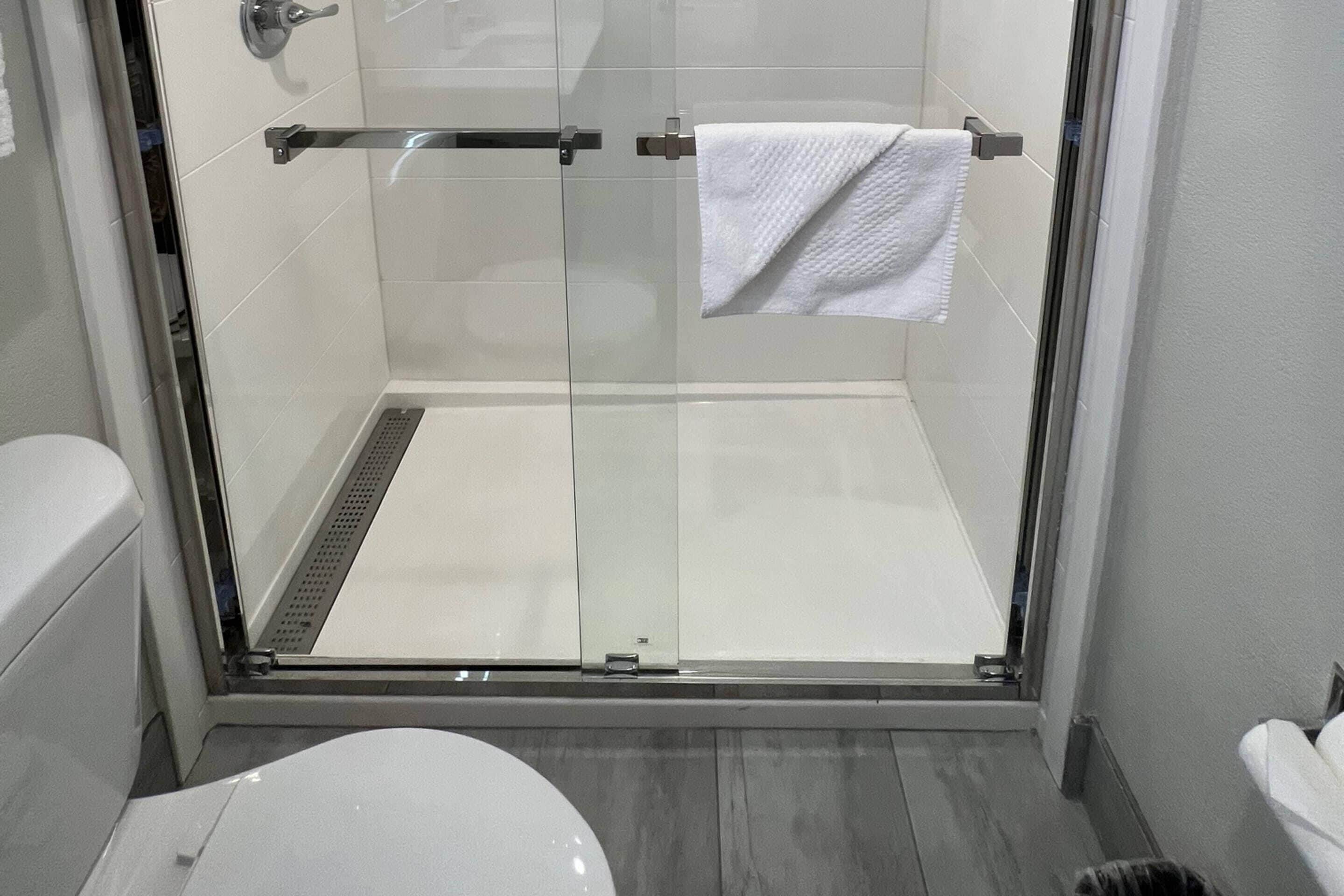 A glass-enclosed shower with a white towel hanging on the door.
