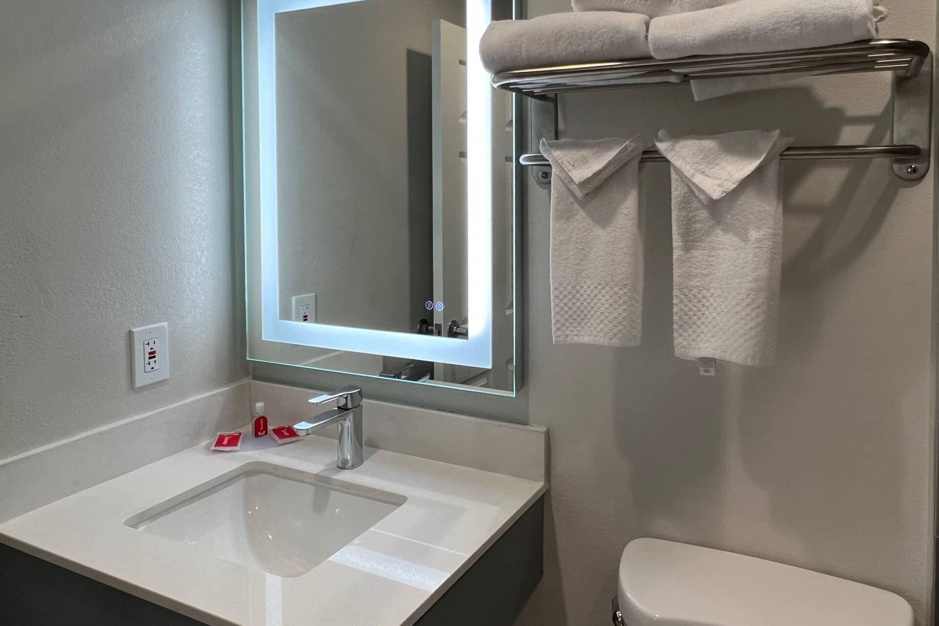 Un bagno con lavandino, specchio, portasciuga e water.