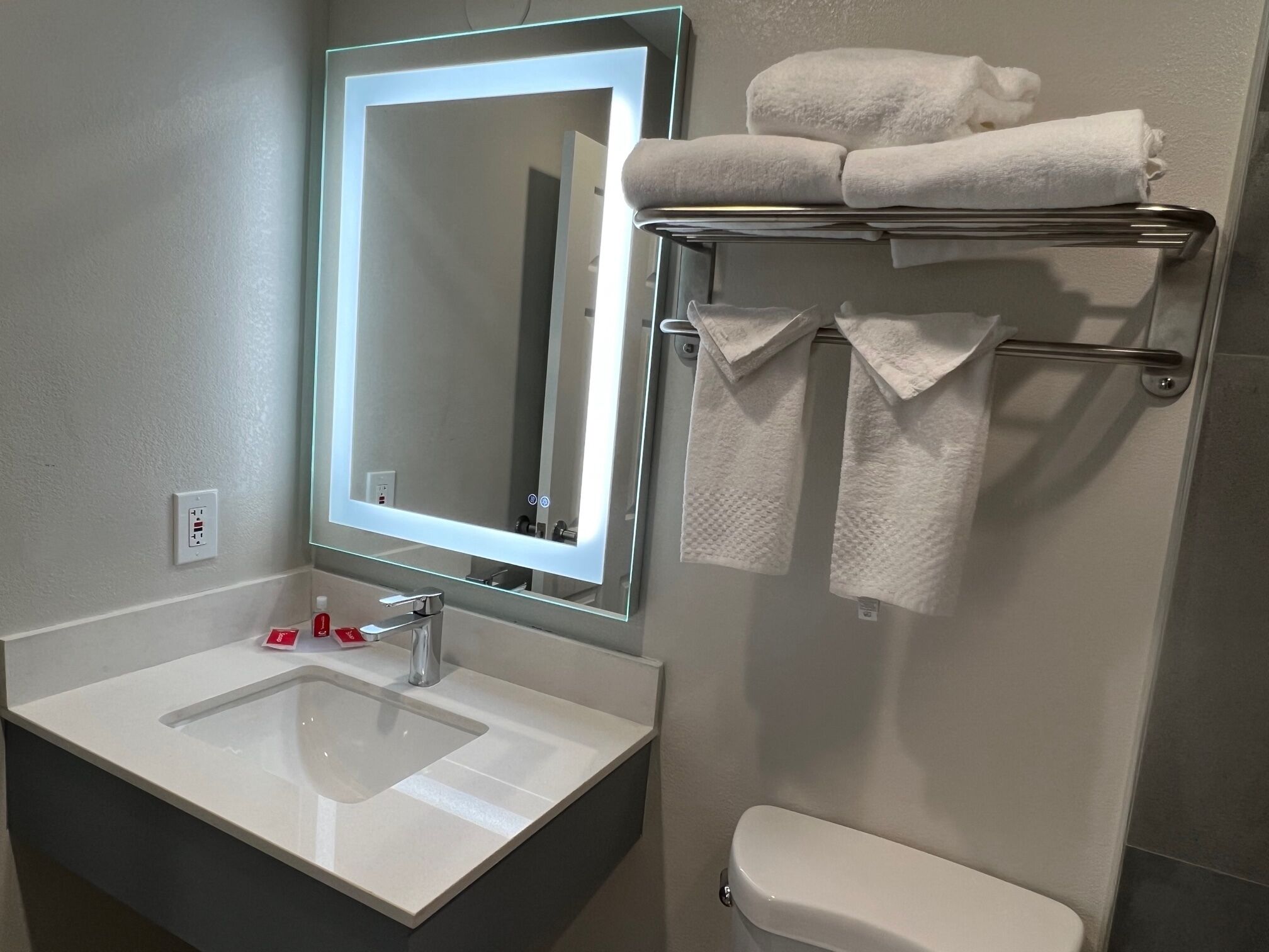 A bathroom with a white sink, a mirror, and a towel rack with towels.
