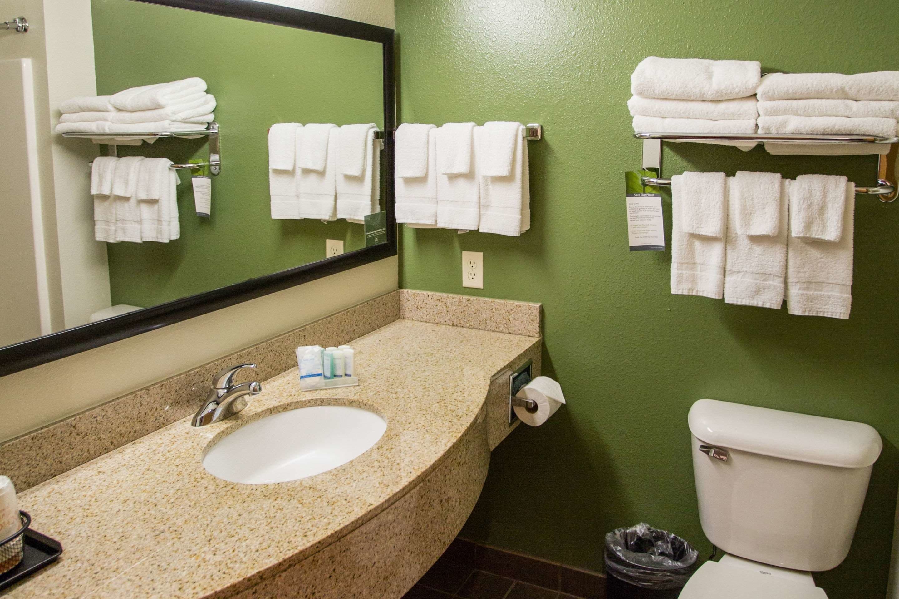 A bathroom with a sink, mirror, towel racks, and a toilet.