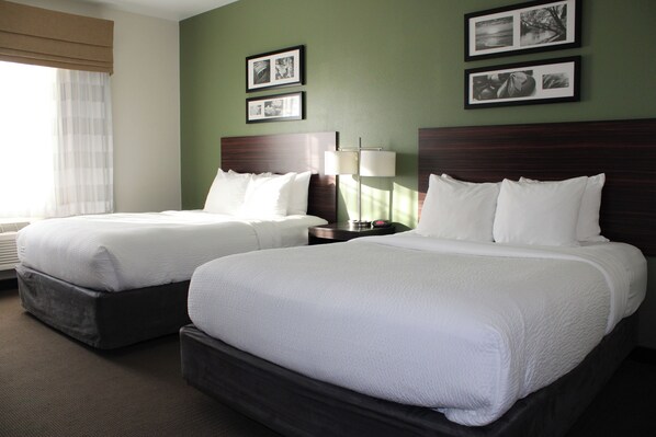 A hotel room with two beds, a nightstand, a lamp, and framed pictures on the wall. - Sleep Inn & Suites Conference Center Eau Claire North (Eau Claire)