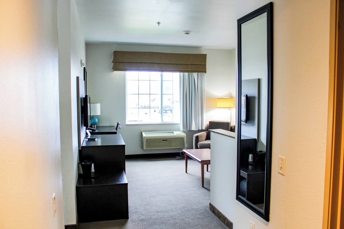 A hotel room with a desk, chair, and a large mirror.