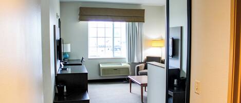 Quarto de hotel com escrivaninha, cadeira e um espelho grande.