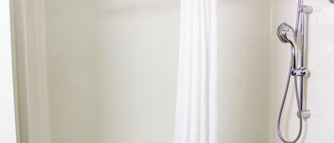Una bañera blanca con ducha, barras de apoyo y una toalla.