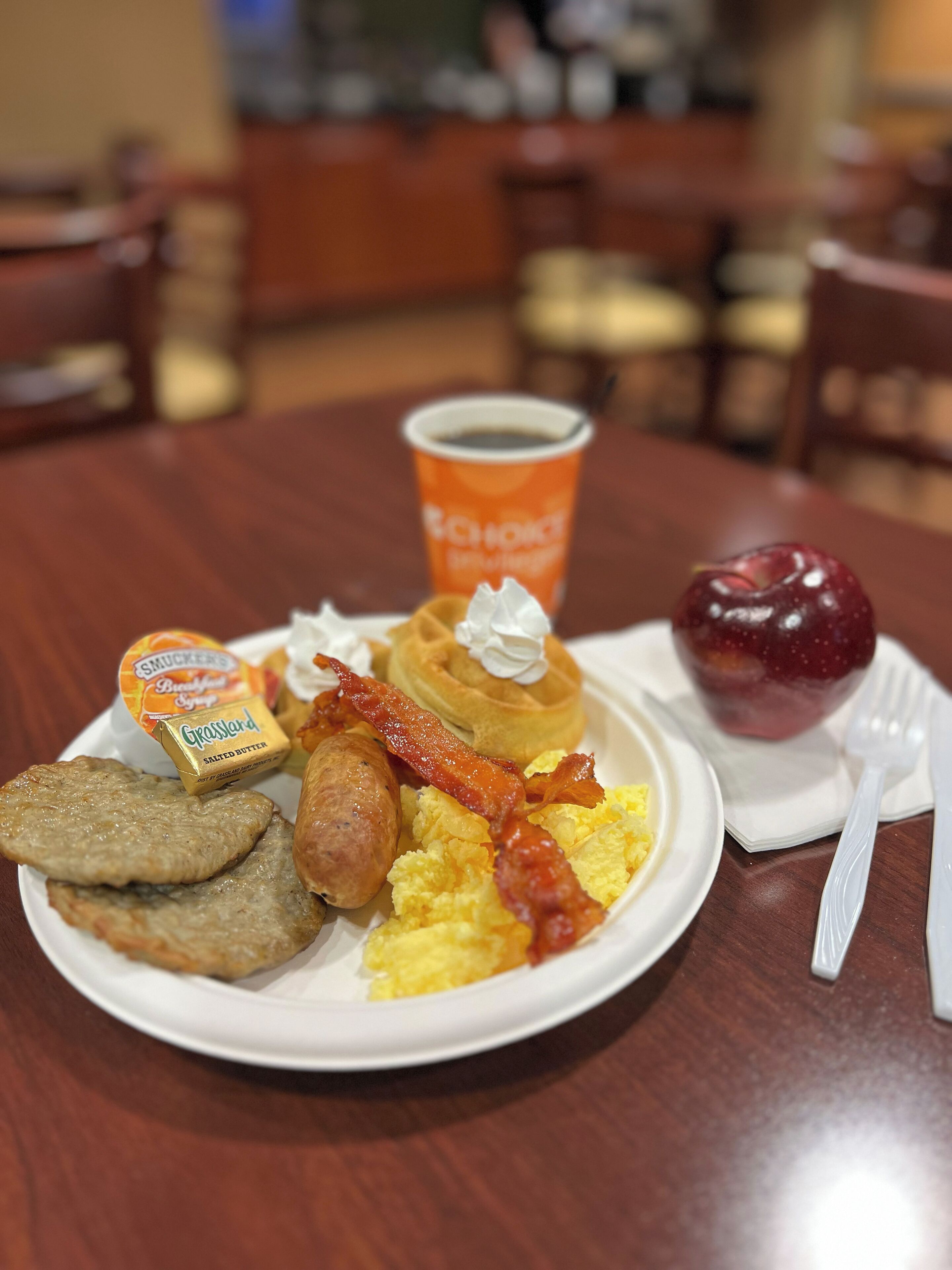 A breakfast plate with eggs, bacon, sausage, and toast.