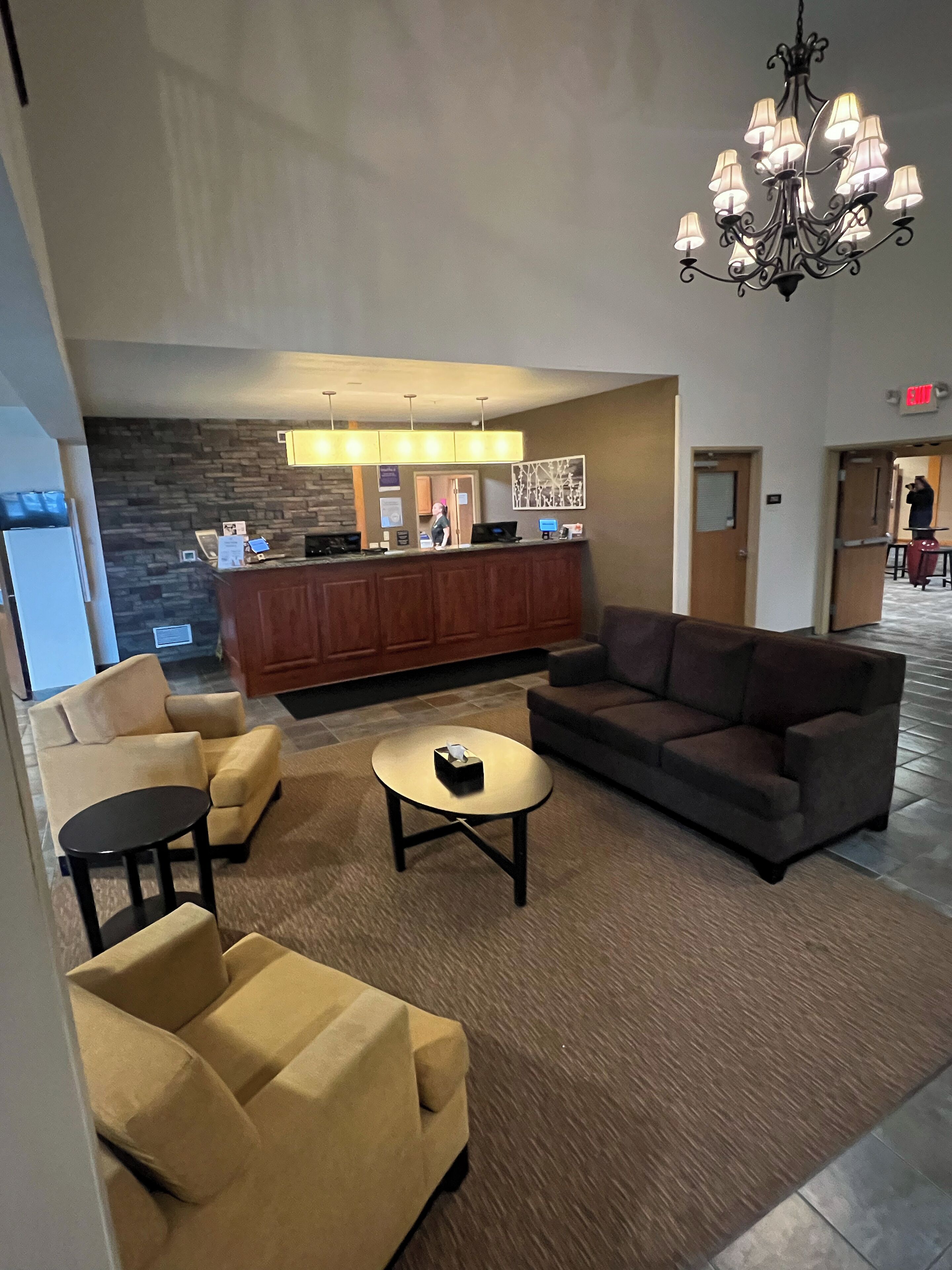 A hotel lobby with a reception desk, a chandelier, sofas, and a coffee table.