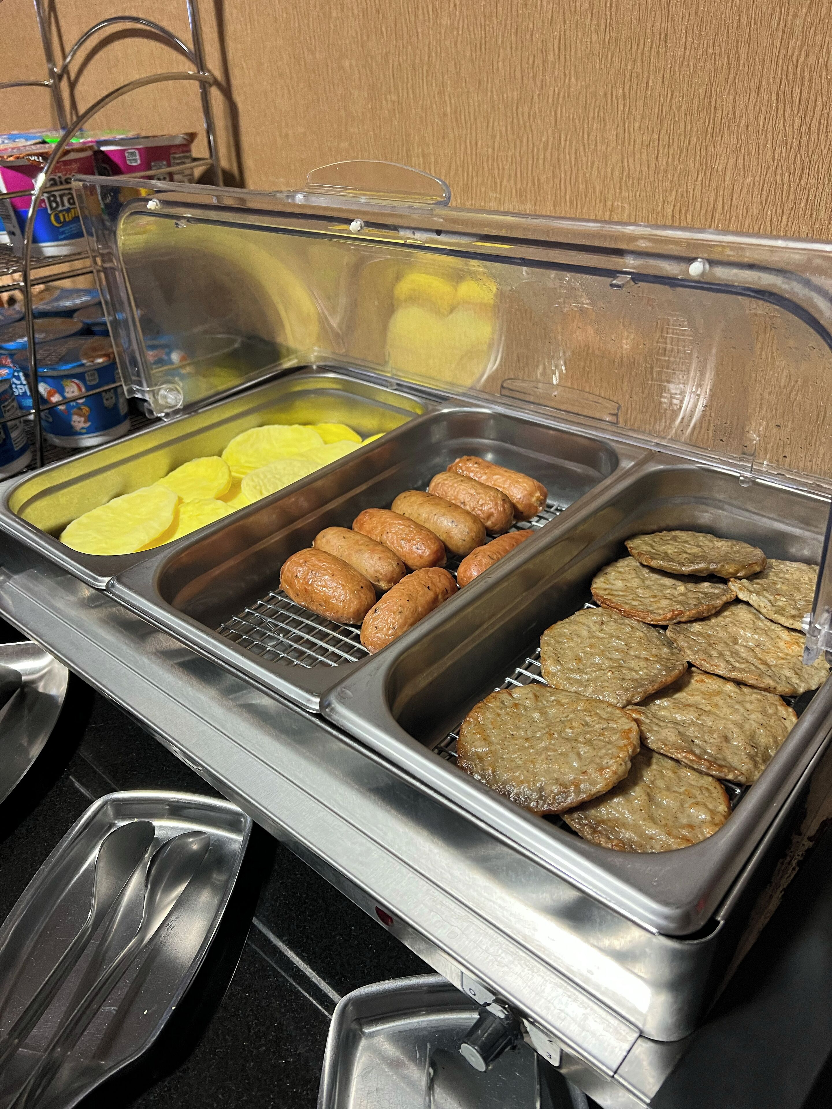 Un bufé con diversos alimentos, incluyendo salchichas, tortitas de patata y otros platos.