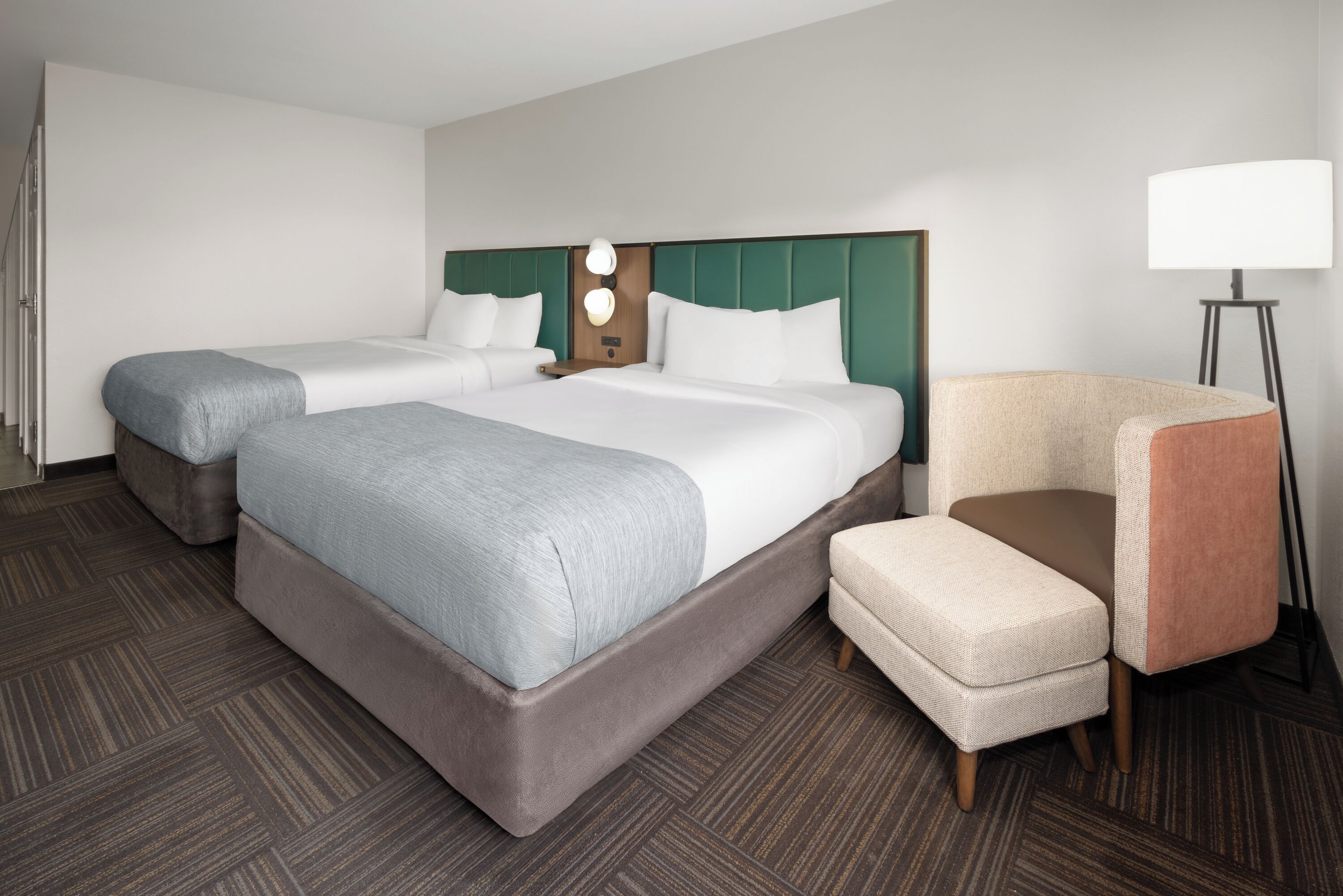 A hotel room with a large bed, two bedside tables, a chair, and a lamp.