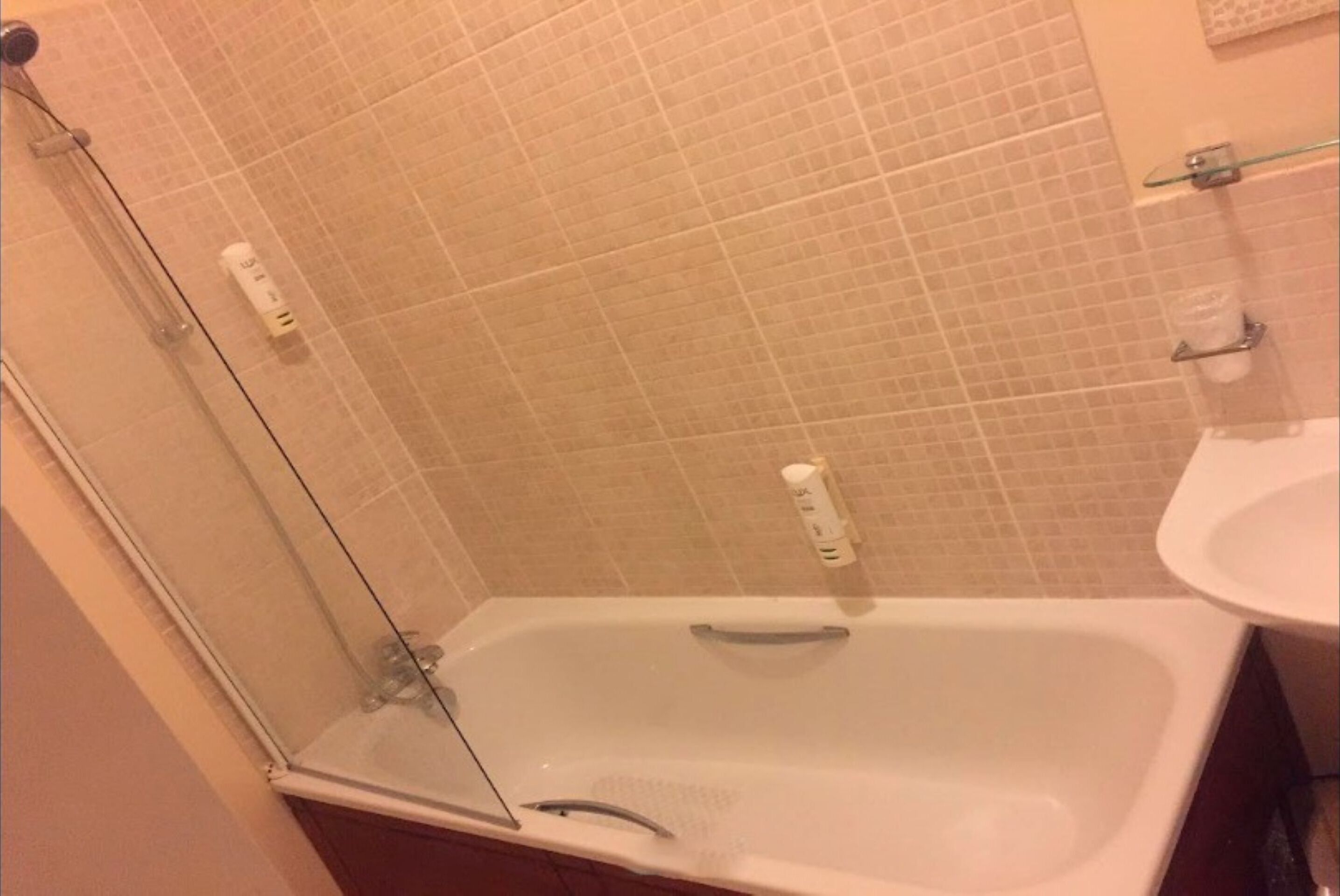 A bathroom with a glass-enclosed shower, a bathtub, and a sink.
