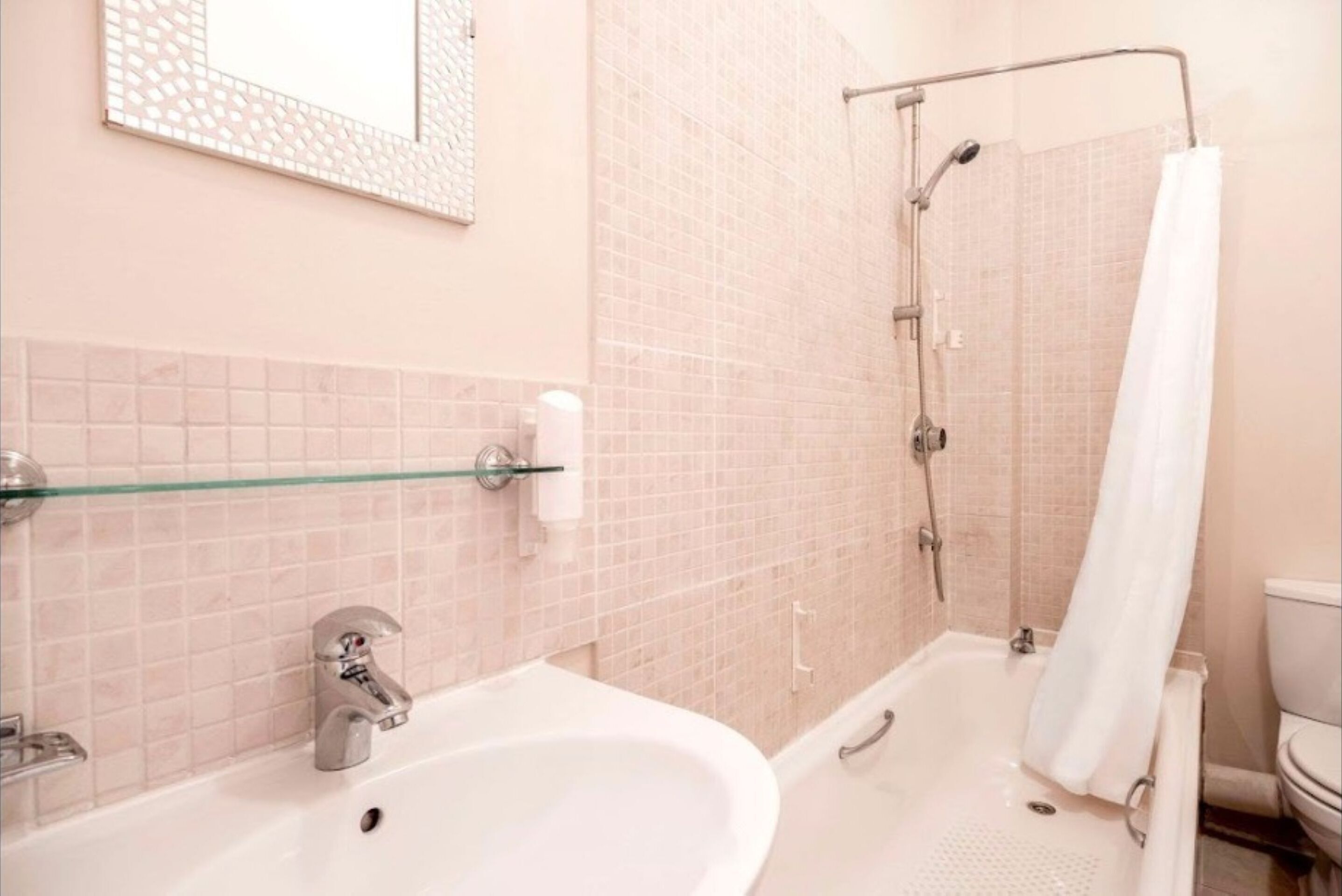 A bathroom with a sink, mirror, and shower.