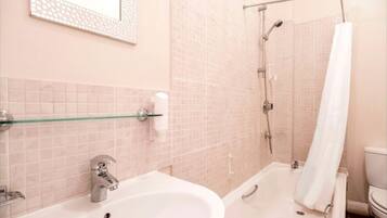 A bathroom with a sink, mirror, and shower.