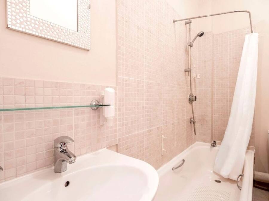 A bathroom with a sink, mirror, and shower.