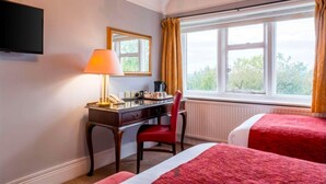 Habitación de hotel con escritorio, silla y dos camas.