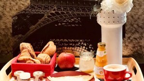 A breakfast tray with bread, an apple, a bottle of juice, and a cup of coffee. - Residence & Spa Le Prince Regent (Paris)