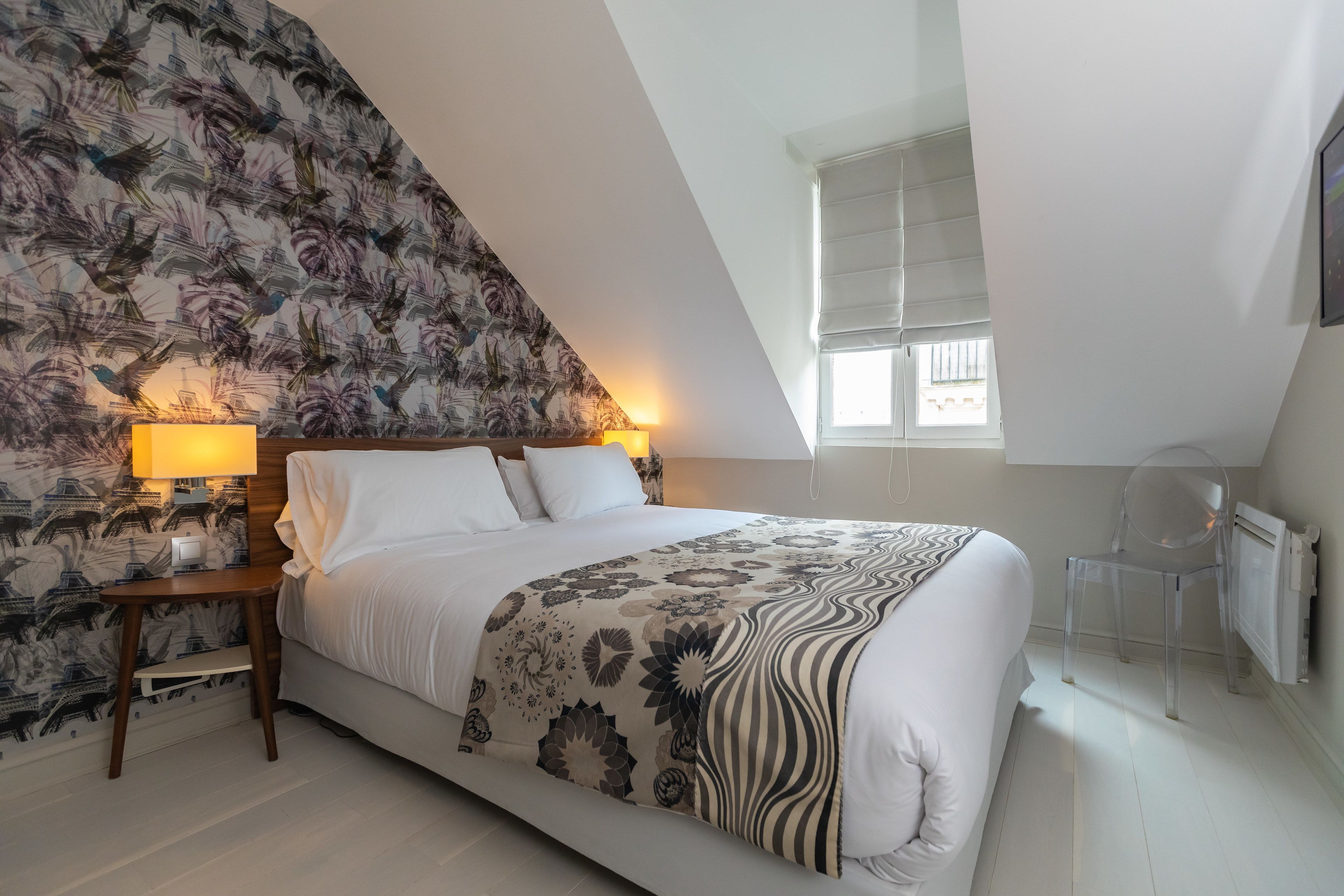 Quarto com cama, mesa de cabeceira, abajur, cadeira e janela.