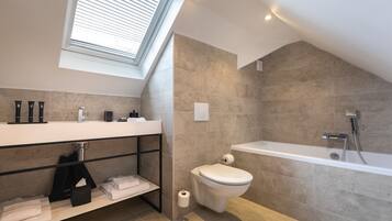 Un baño moderno con tragaluz, bañera e inodoro.